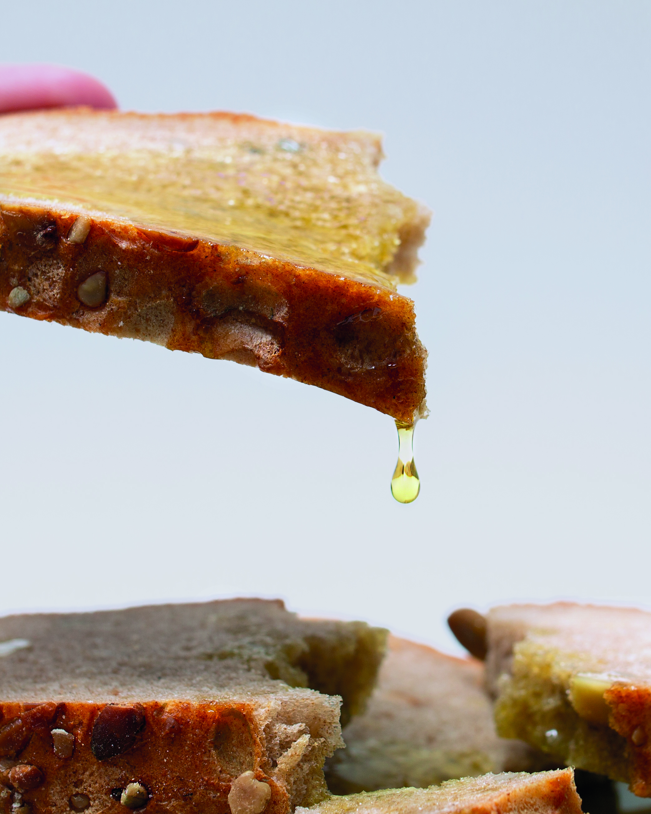 Green olives on a plate with oil drizzled from a spoon